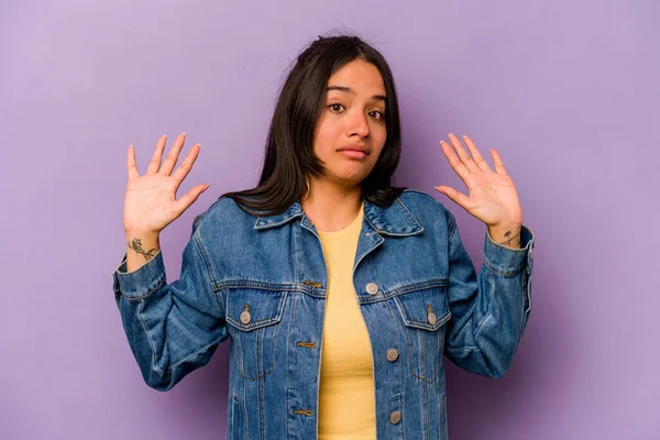 Mor arka planda izole edilmiş genç İspanyol kadın yakın bir tehlike nedeniyle şoka uğruyor.