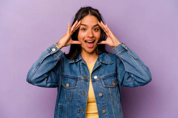 Mor arka planda izole edilmiş genç İspanyol kadın hoş bir sürprizle karşılaşıyor, heyecanlı ve el kaldırıyor..