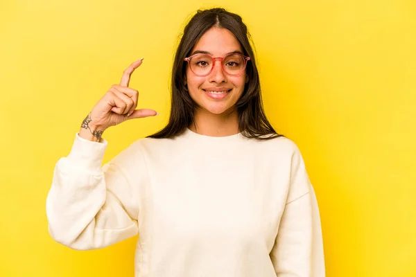 Young Hispanic Woman Isolated Yellow Background Holding Something Little Forefingers — Fotografia de Stock