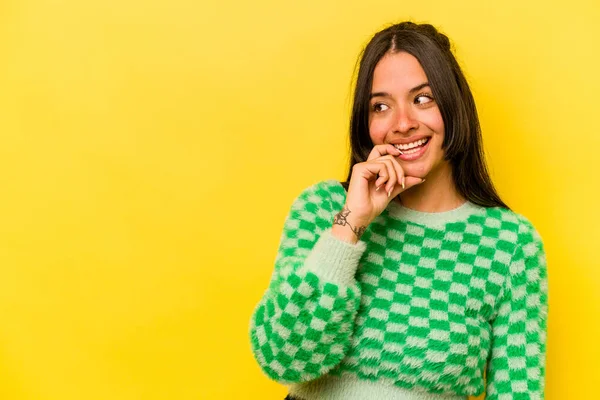 Sarı arka planda izole edilmiş genç İspanyol kadın rahatlamış bir şeyin fotokopi odasına baktığını düşünüyor..