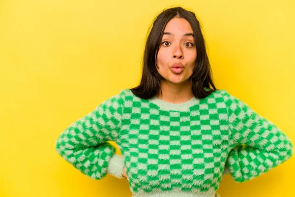 Sarı arka planda izole edilmiş genç İspanyol kadın gördüğü bir şey yüzünden şoka uğruyor..