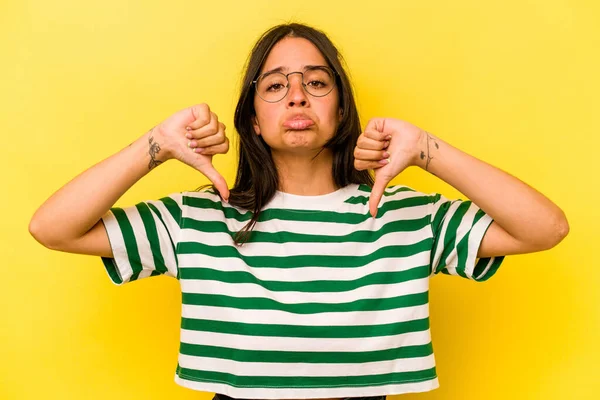 Sarı arka planda izole edilmiş genç İspanyol kadın hoşlanmadığı bir hareket gösteriyor. Anlaşmazlık konsepti.
