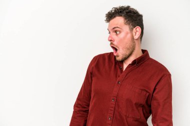 Beyaz arka planda izole edilmiş genç beyaz adam gördüğü bir şey yüzünden şoka uğruyor..