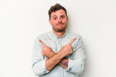 Beyaz arka plan noktalarında izole genç beyaz adam, iki seçenek arasında seçim yapmaya çalışıyor.