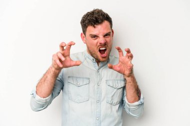 Beyaz arka planda izole edilmiş genç beyaz bir adam pençelerini kedi taklidi yaparken gösteriyor, agresif bir hareket..