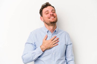 Beyaz arka planda izole genç beyaz adam yüksek sesle gülüyor elini göğsüne koyuyor..