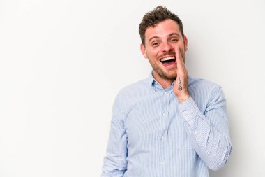 Beyaz arka planda izole genç beyaz adam yüksek sesle bağırıyor, gözleri açık ve elleri gergin tutuyor..