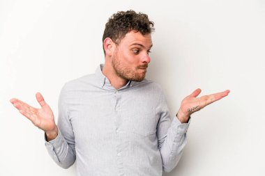 Beyaz arka planda izole edilmiş genç beyaz bir adam. Kafası karışmış ve omuz silkiyor. Kopya alanını tutmak için..