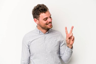 Beyaz arka planda izole edilmiş genç beyaz bir adam neşeli ve kaygısız parmakları olan bir barış sembolü gösteriyor..
