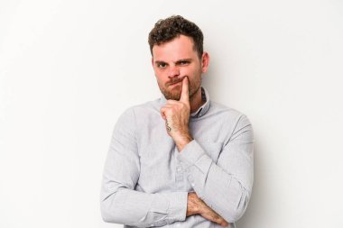 Beyaz arka planda izole edilmiş genç beyaz adam alaycı bir ifadeyle kameraya bakıyor..