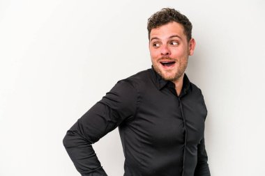 Beyaz arka planda izole edilmiş genç beyaz adam gülümseyen, neşeli ve keyifli bir tarafa bakıyor..