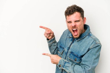 Beyaz arka planda izole edilmiş genç beyaz bir adam işaret parmağıyla fotokopi alanını işaret ederek heyecan ve arzusunu ifade ediyor..