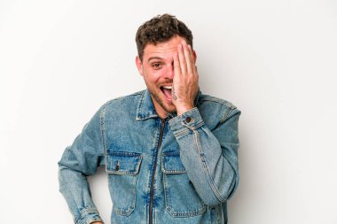 Beyaz arka planda izole edilmiş genç beyaz bir adam yüzünün yarısını palmiye ile örterek eğleniyor..