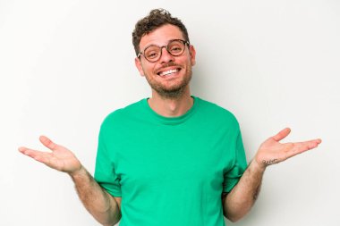 Beyaz arka planda izole genç beyaz adam kollarıyla ölçek yapar, mutlu ve kendinden emin hisseder..