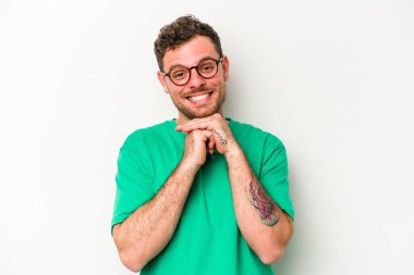 Beyaz arka planda izole genç beyaz adam ellerini çenesinin altında tutuyor, mutlu bir şekilde yana bakıyor..