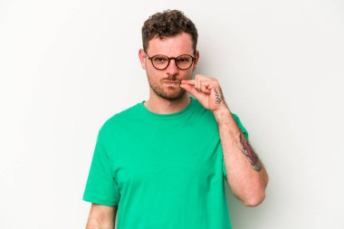 Beyaz arka planda izole edilmiş beyaz tenli genç bir adam parmakları dudaklarında bir sır saklıyor..