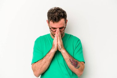 Beyaz arka planda izole edilmiş genç beyaz adam dua ediyor, bağlılık gösteriyor, dindar biri ilahi ilham arıyor..