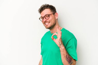 Beyaz arka planda izole edilmiş genç beyaz bir adam bir göz kırptı ve elleriyle iyi bir jest yaptı..