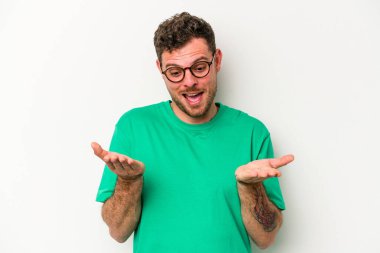 Beyaz arka planda izole edilmiş genç beyaz bir adam elinde avuç içi bir şeyle kameraya sunuyor..