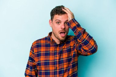 Mavi arka planda izole genç beyaz adam şok oldu, o önemli bir toplantı hatırladı.