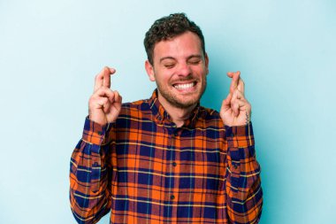 Kafkasyalı genç adam mavi arka planda izole edilmiş şans dilemek için şans diliyor.