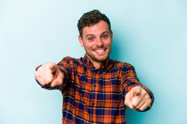 Mavi arka planda izole edilmiş genç beyaz adam öne bakan neşeli gülümsemeler.