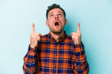 Mavi arka planda izole edilmiş beyaz bir adam ağzı açık bir şekilde üst tarafı işaret ediyor..