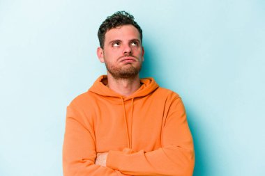 Mavi arka planda izole edilmiş genç beyaz adam tekrarlanan bir görevden yoruldu..