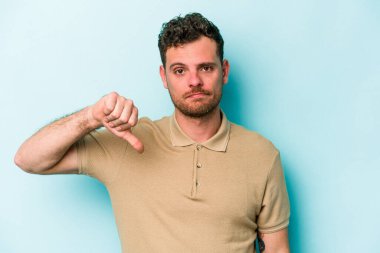 Mavi arka planda izole edilmiş genç beyaz bir adam hoşlanmadığı bir jest yapıyor. Anlaşmazlık konsepti.