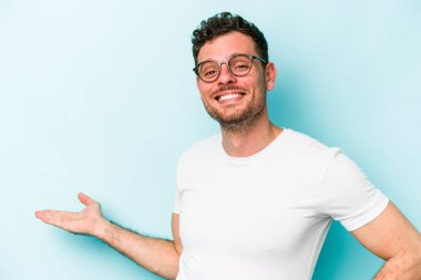 Mavi arka planda izole edilmiş beyaz bir genç hoş bir yüz ifadesi sergiliyor..