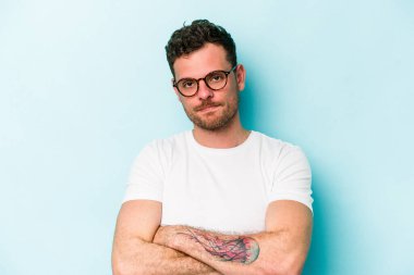 Mavi arka planda izole edilmiş, sıkılmış, yorgun ve dinlenmeye ihtiyacı olan genç beyaz bir adam..