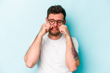 Kafkasyalı genç adam mavi arka planda izole edilmiş sızlanıyor ve ağlıyordu..