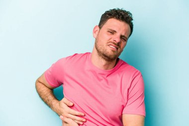 Mavi arka planda karaciğer ağrısı çeken, karnı ağrıyan genç beyaz bir adam..