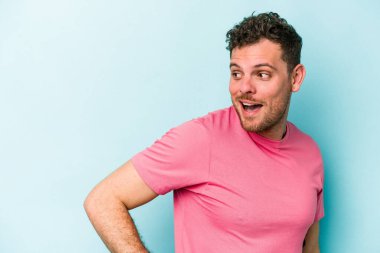 Mavi arka planda soyutlanmış genç beyaz bir adam gülümsüyor, neşeli ve keyifli görünüyor..
