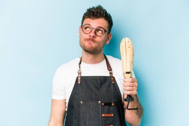 Kafkasyalı genç kunduracı, mavi arka planda izole edilmiş, hedeflerine ve amaçlarına ulaşma hayali kuruyor.