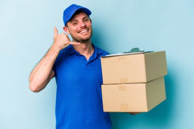 Mavi arka planda izole edilmiş genç beyaz teslimatçı parmakları olan bir cep telefonu hareketi gösteriyor..