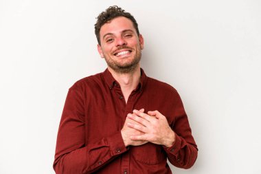 Beyaz arka planda izole edilmiş beyaz tenli genç bir adam, dostane bir ifadeye sahip, avuçlarını göğsüne bastırıyor. Aşk konsepti.