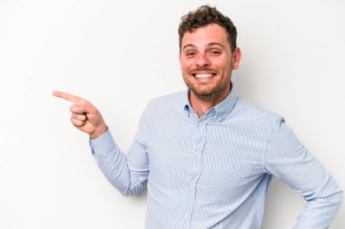 Beyaz arka planda izole edilmiş genç beyaz adam işaret parmağıyla işaret ederek gülümsüyor..