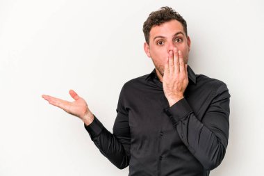 Beyaz arka planda izole edilmiş genç beyaz adam, avuç içi fotokopi alanını elinde tutmaktan etkilenmiş..