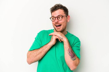 Beyaz arka planda izole edilmiş genç beyaz bir adam şans için dua ediyor, şaşırmış ve ağzını açıp önüne bakıyor..