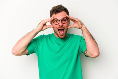 Beyaz arka planda izole genç beyaz adam hoş bir sürpriz alıyor, heyecanlı ve el kaldırıyor..