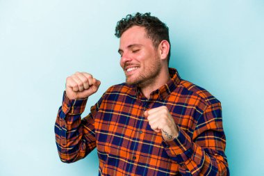 Genç beyaz adam mavi arka planda izole edilmiş dans ediyor ve eğleniyor..