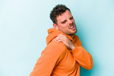 Mavi arka planda izole edilmiş, omuz ağrısı olan genç beyaz bir adam..