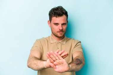 Mavi arka planda izole edilmiş genç beyaz adam elini uzatmış, dur işareti göstererek seni engelliyor..