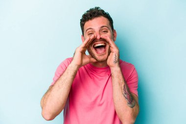 Kafkasyalı genç adam mavi arka planda izole edilmiş. Dedikodu yapıyor, bir şeyleri bildiriyor..