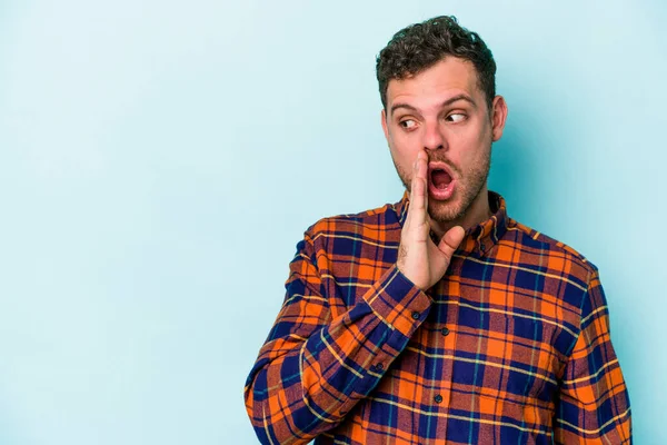 Mavi arka planda izole edilmiş genç beyaz bir adam gizli bir sıcak fren haberi veriyor ve yana bakıyor.