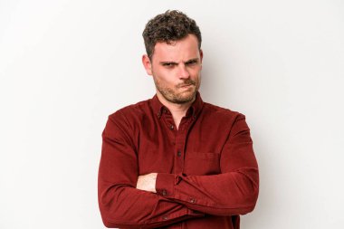 Beyaz arka planda izole edilmiş, hoşnutsuzca kaşlarını çatmış, kollarını kavuşturmuş genç beyaz bir adam..