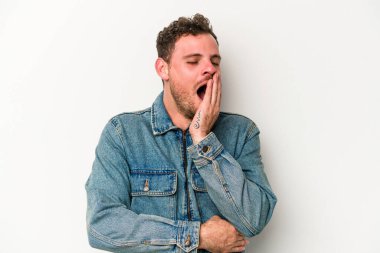 Beyaz arka planda izole edilmiş genç beyaz adam esniyor. Ağzı eliyle kapatan yorgun bir hareket sergiliyor..