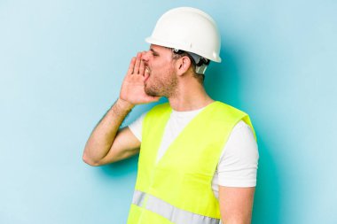 Beyaz tenli genç işçi mavi arka planda izole edilmiş bağırıyor ve avuç içini açık tutuyordu..