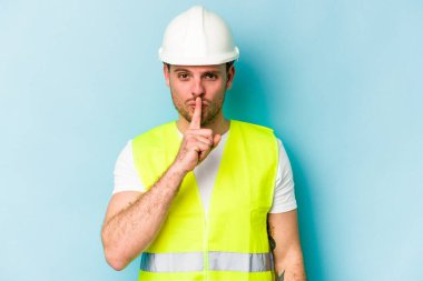 Genç beyaz adam mavi arka planda izole edilmiş bir şekilde bir sır saklıyor ya da sessizlik istiyor..